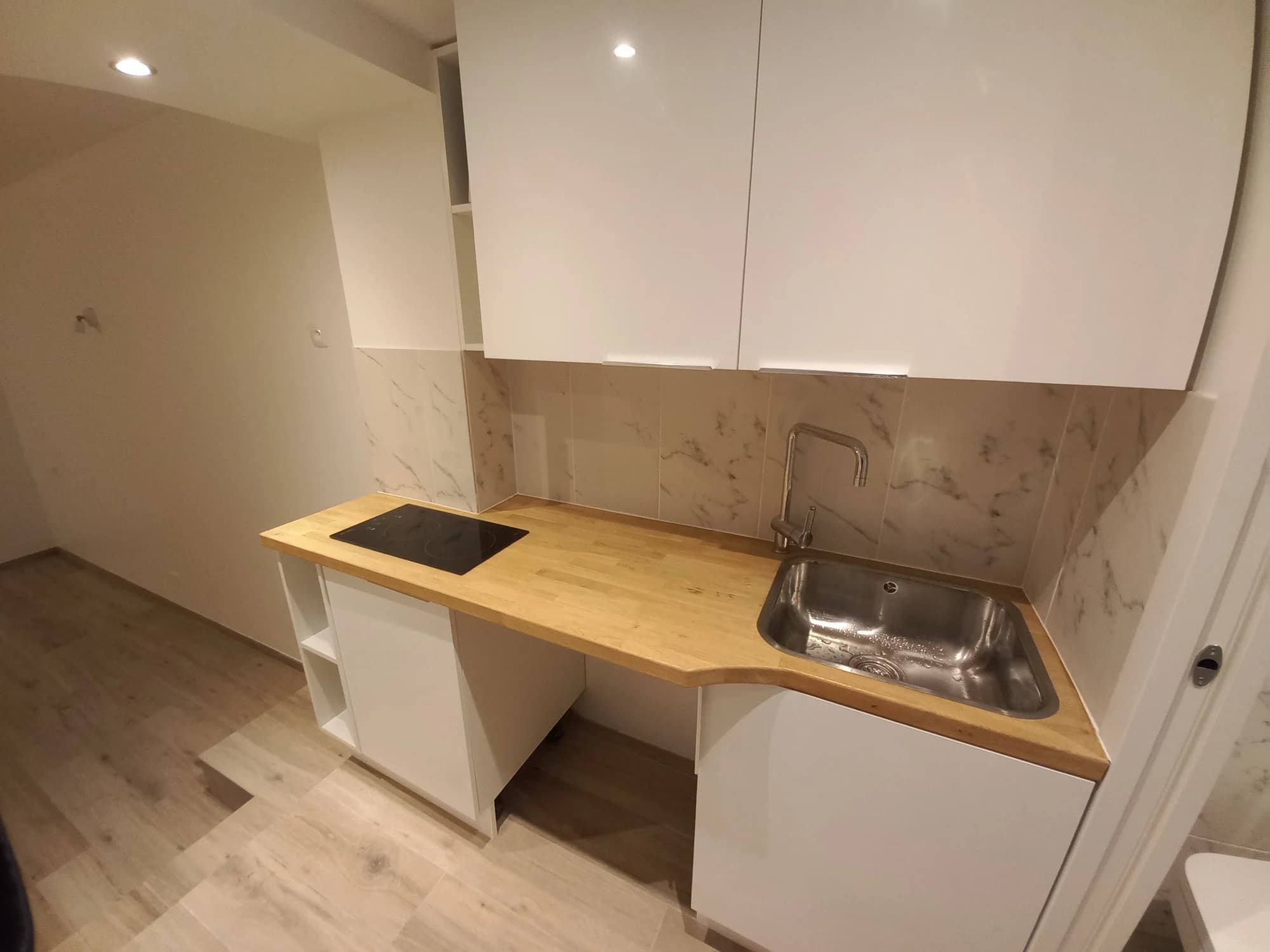Plan de travail en bois, évier et plaque de cuisson dans la cuisine de l’appartement parisien.