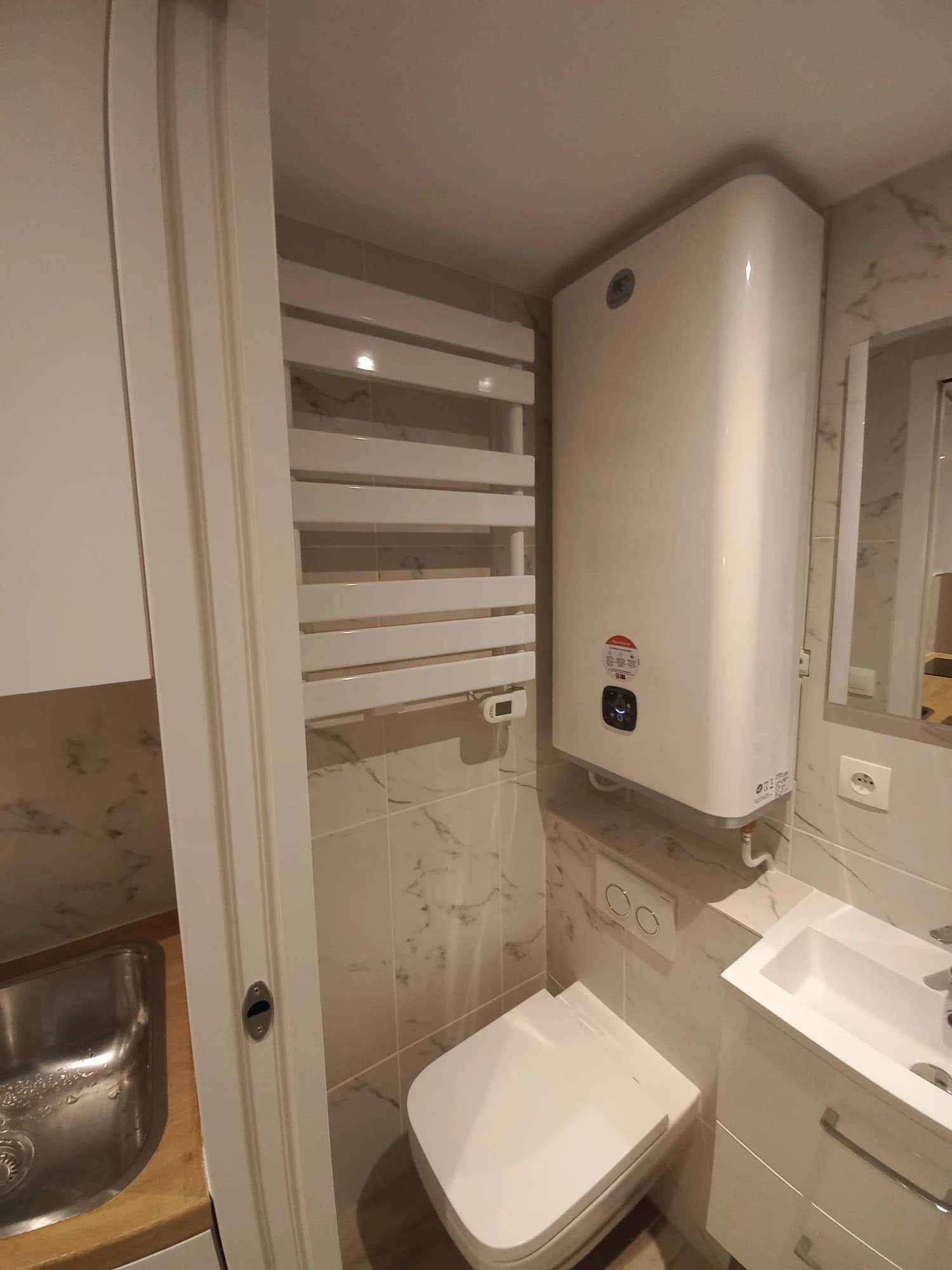 Équipements de la salle d’eau de l’appartement parisien avec WC et sèche-serviettes.