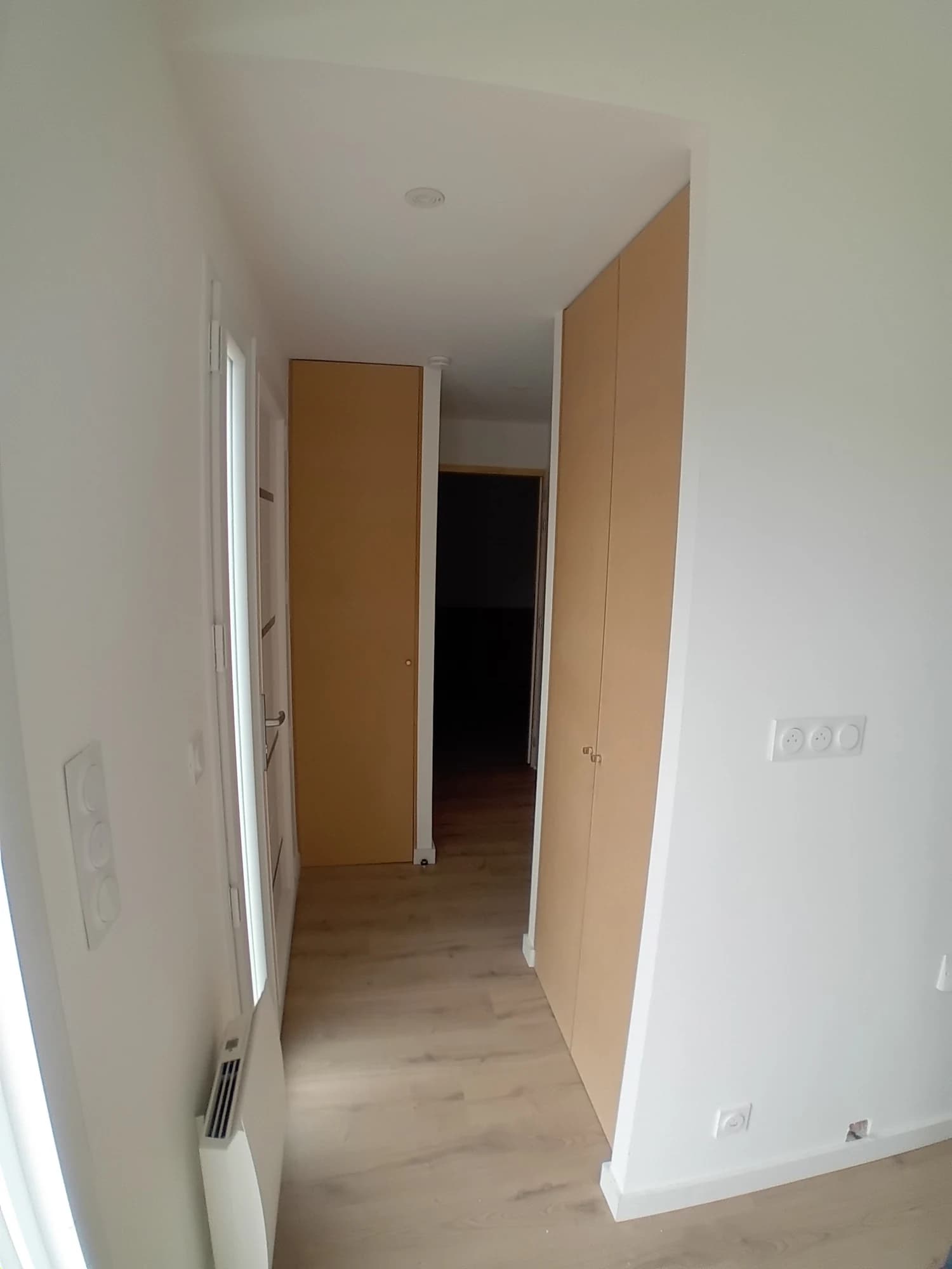 Circulation intérieure à Quiberon, avec parois claires et porte en bois.