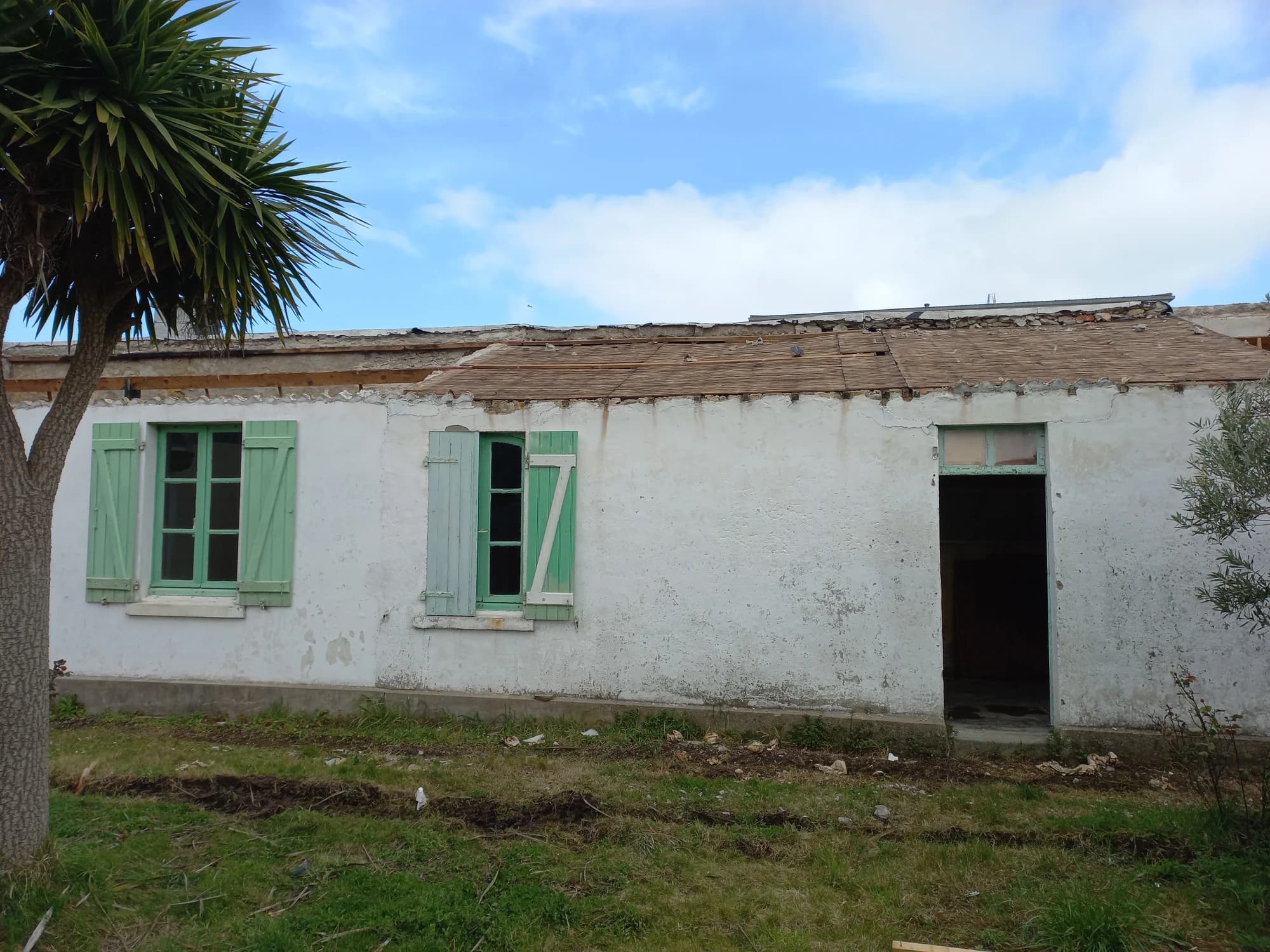 Bâtiment existant à Quiberon avant les travaux, avec façade blanche et volets verts.