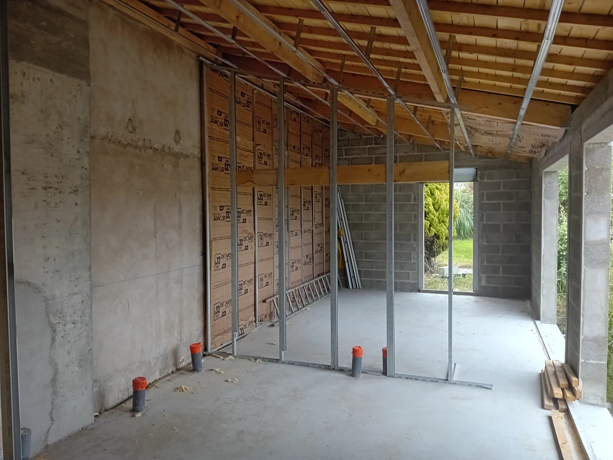 Intérieur de l’extension à Quiberon pendant le chantier, avec charpente visible et étaiement.
