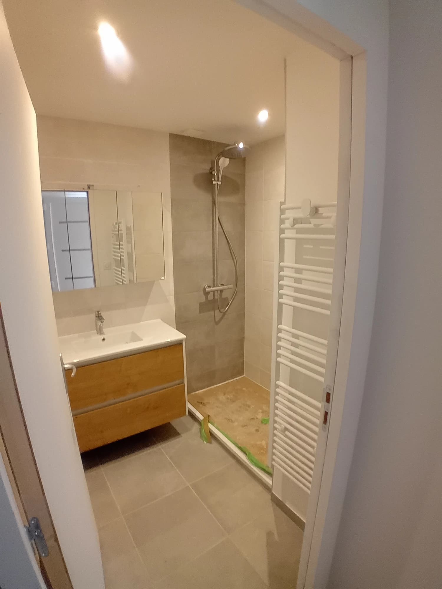 Salle d’eau à Quiberon avec douche vitrée, meuble vasque en bois et sèche-serviettes.
