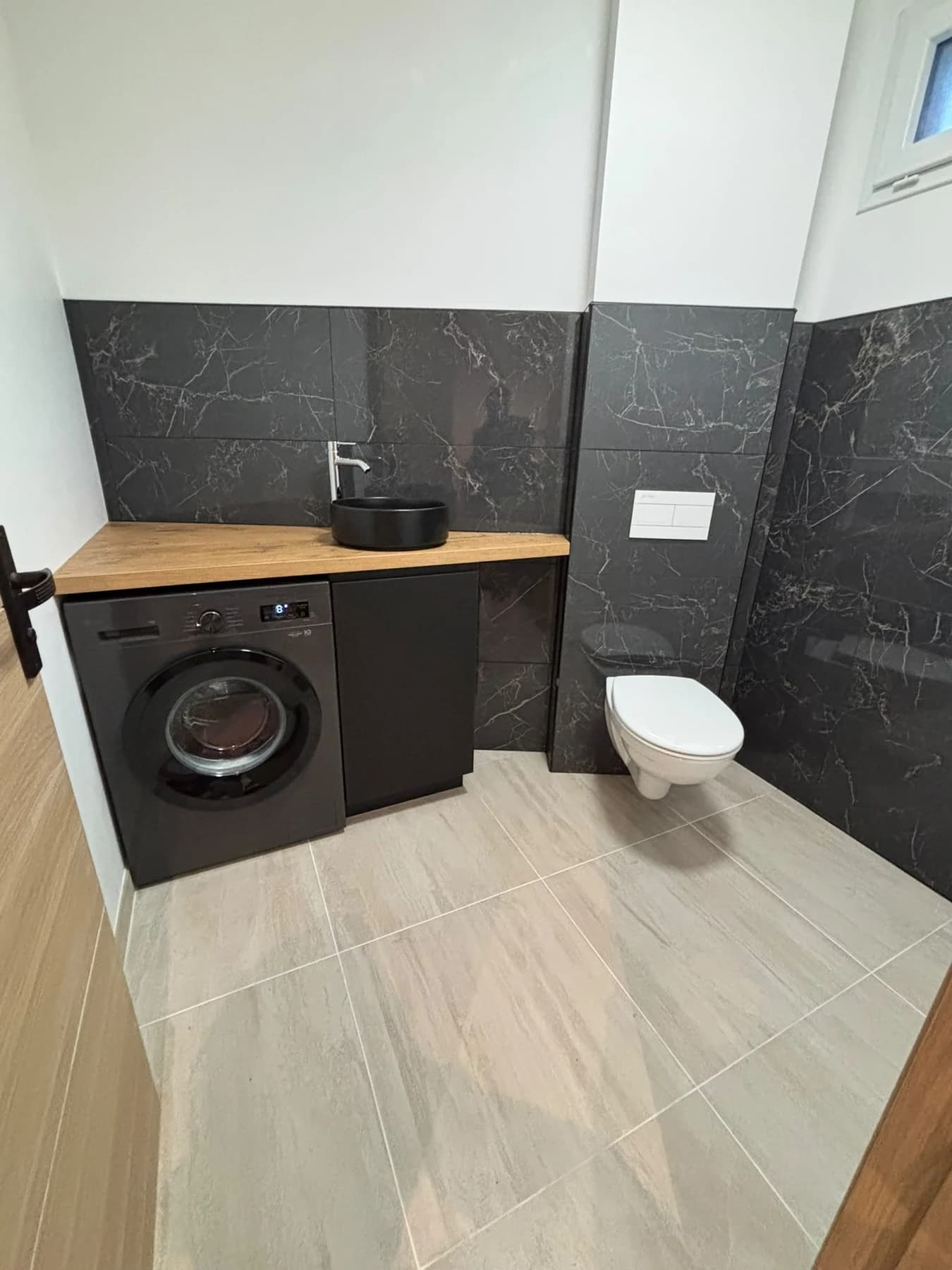 Pièce d’eau avec plan vasque, lave-linge et sanitaires dans la maison rénovée.